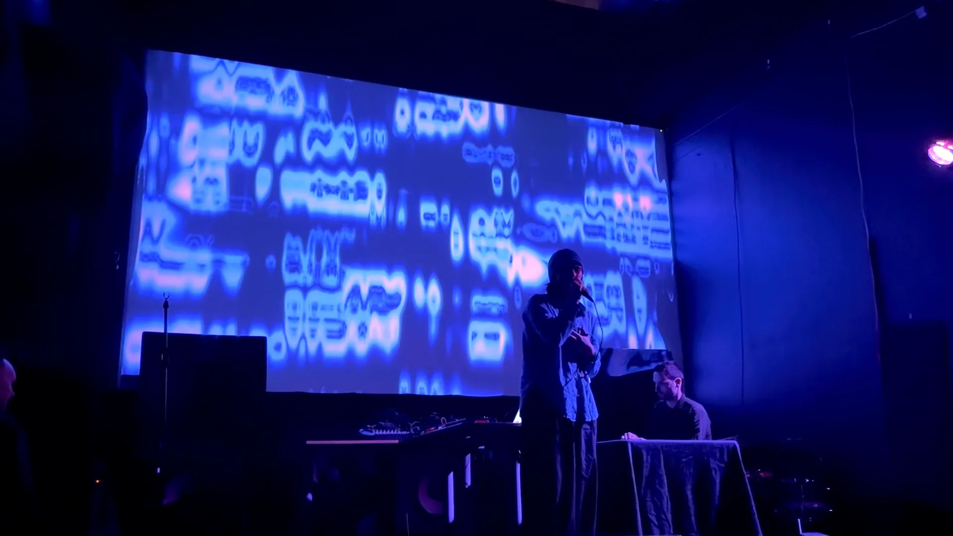 Melisa performing while bright blue lines drift across the screen and melt into liquid shapes.